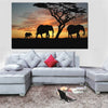 Un elephant, une elephante et un elephanteau de couleur noire devant un paysage orange